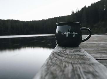 a mug on a deck overlooking a lake