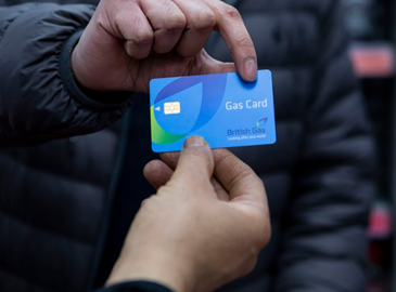 A man passes a British Gas top-up card to another person