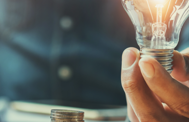 lightbuld held next to coins