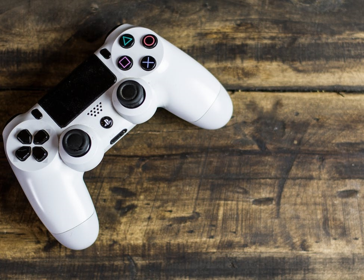 A white Playstation game controller on a wooden table top