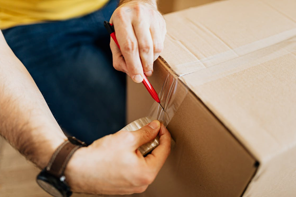 A man applying sellotape to a parcel