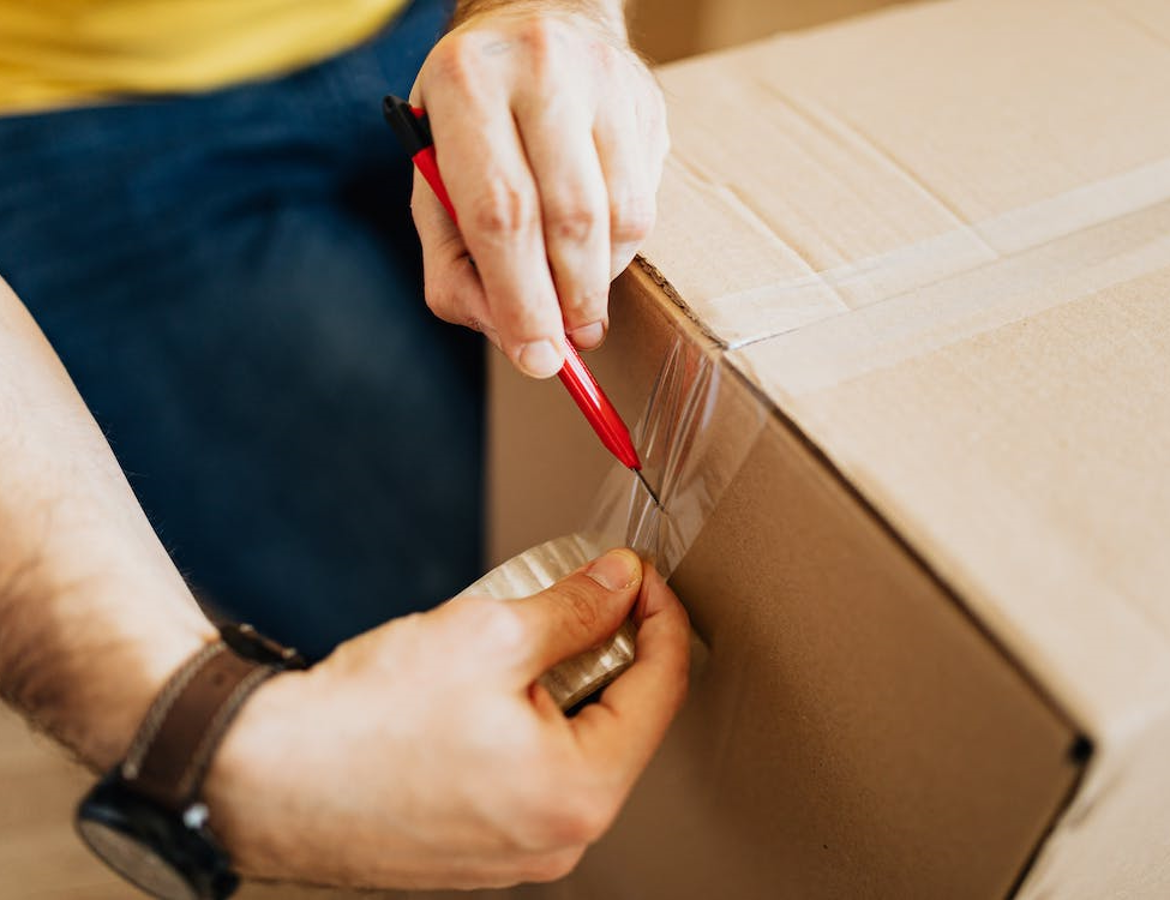 A man applying sellotape to a parcel