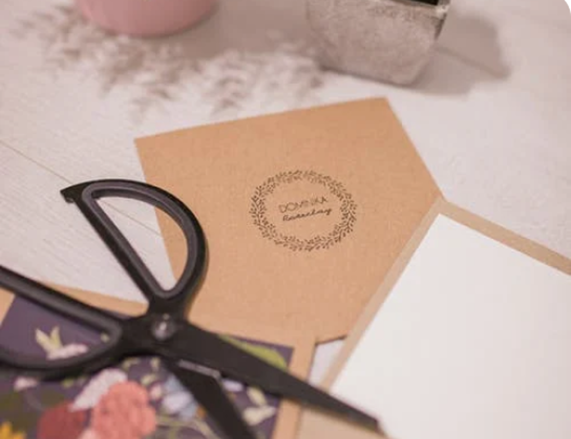 A brown gift card with a pair of black scissors