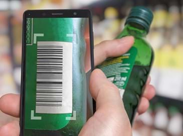 A retail employee scans a bottle of alcohol