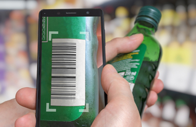 A retail employee scans a bottle of alcohol